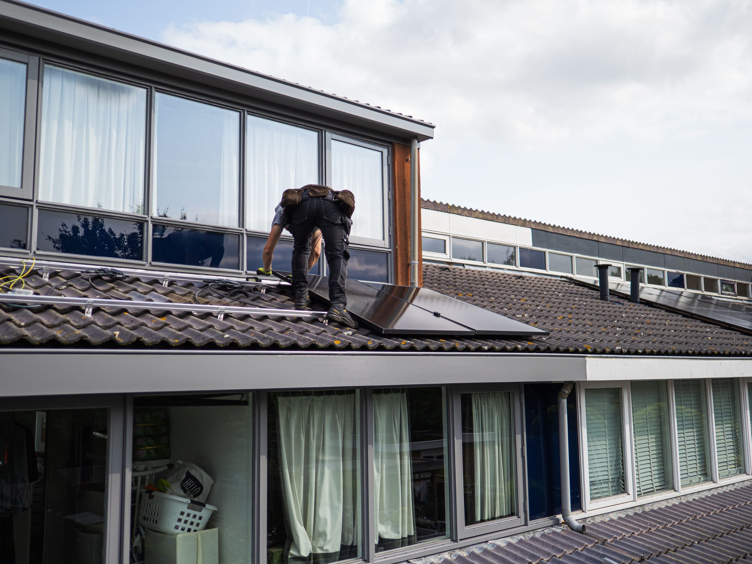 Solar technician installing panels on a residential rooftop